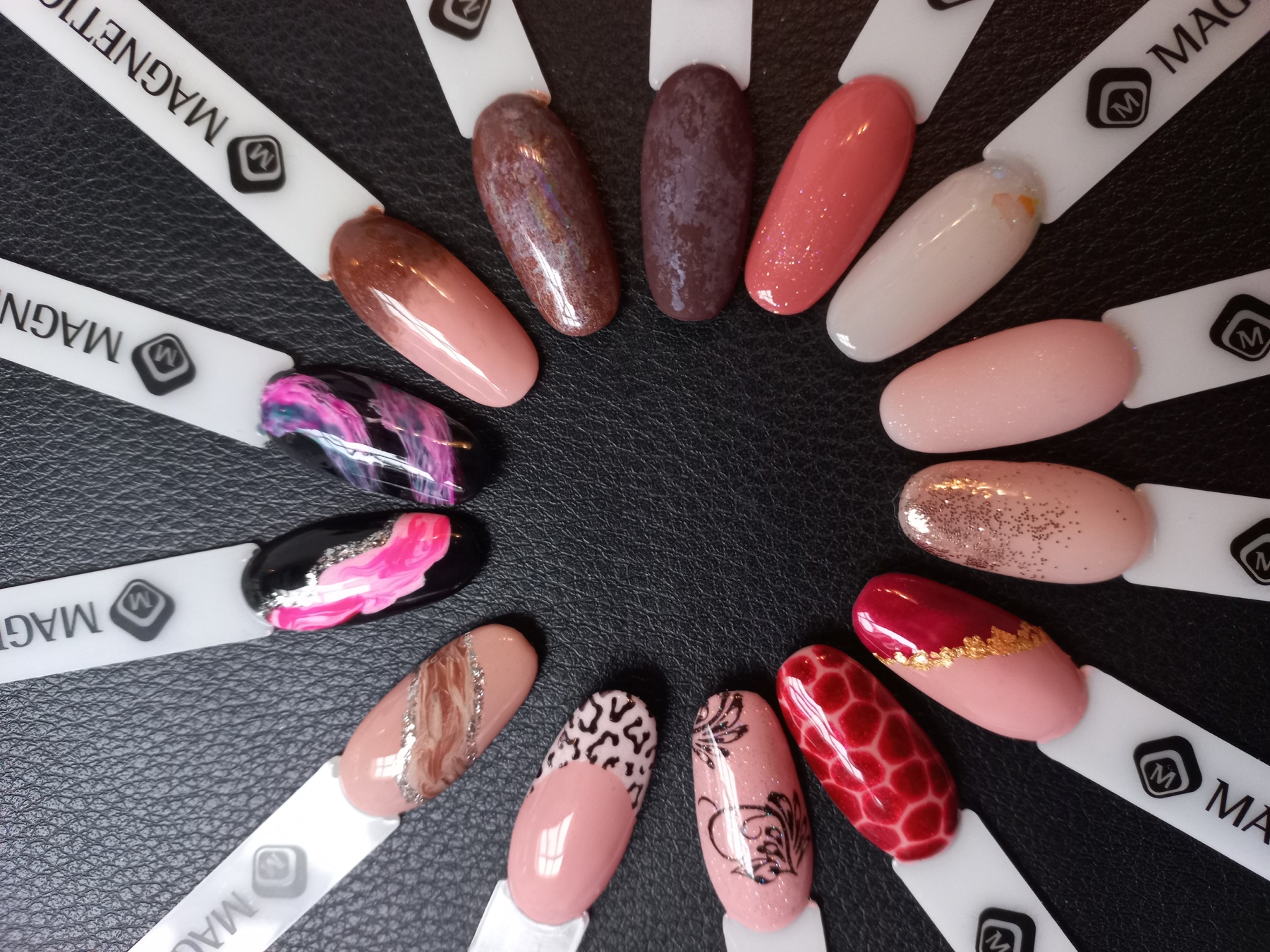 Waaier met voorbeelden van roze, rode en zwarte nailart